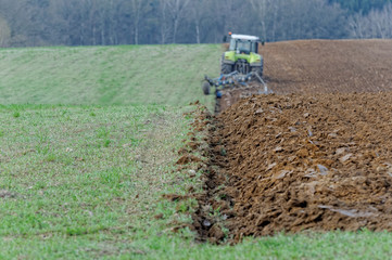 Traktor uprawiający ziemię na polu. 