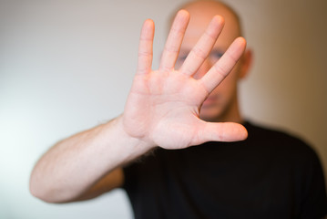 Serious young man showing stop gesture isolated on gray wall background