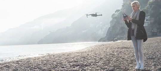 Young girl flying drone over italian coast.