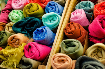 many pashmina foulards rolled up in a wooden crate on a market stall