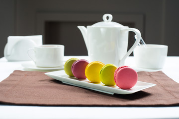 Colorful macaroons on a white square plate Sweet macarons and flowers.