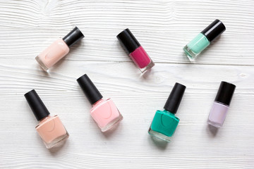 collection of nail polish on white desk background top view