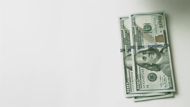 Splitting money into two unequal stacks. Men's hand puts hundred-dollar bills on the table, and then takes them away.