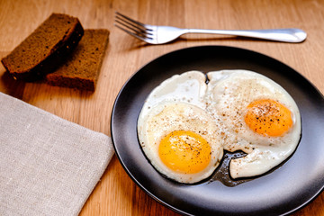fried egg on black plate on wooden table