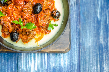 Frying pan with potatoes, minced meat, olives and herbs