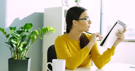 Attractive woman writing on daily notebook at the office. Business woman writing notes in notebook. - Powered by Adobe