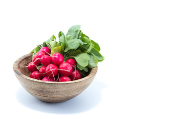 Fresh radish with green leaves in a natural wood bowl isolated in white background