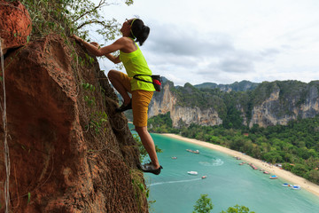 Naklejka premium free solo woman rock climber climbing at seaside cliff