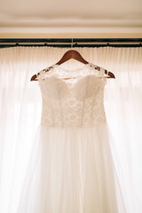 The bride's dress hangs on the cornice on the window.