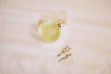 Women's perfume and earrings lying on the bed. Wedding bride's accessories.