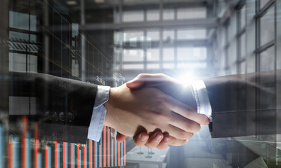 Partners shaking hands as symbol of deal . Mixed media