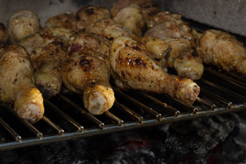 Grilled chicken legs thighs on a grill with a lit fire barbecue