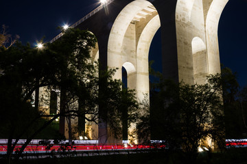Fototapeta premium Night view of the arches of the Cabrillo bridge in San Diego, California, with car trails on the 163 freeway. 