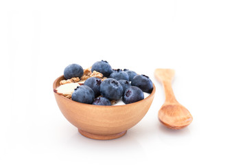 Yogurt with granola and organic blueberries in wooden bowl.