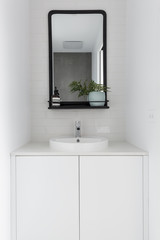 Fototapeta na wymiar Monochrome powder room vanity black mirror and white tiling