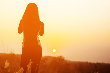 Silhouette woman taking photo of sunset by using smart phone