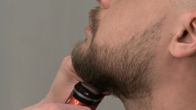 Barber shop, the Barber trims the beard of a bearded man