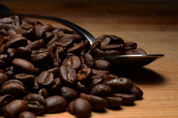 Fresh Coffee Beans on a Wooden Surface with a Spoon in the Background