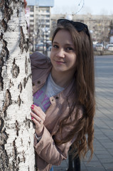 The young woman stands near a tree in the park.