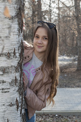 The young woman stands near a tree in the park.