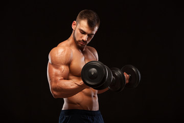 Fototapeta na wymiar Muscular handsome man is training with dumbbells in gym. isolated on black background with copyspace