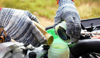 Hand of technician checking or fill oil engine of modern car.