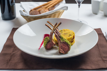 Rack of lamb grilled with porridge of millet on a white plate