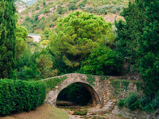 Fototapeta na wymiar Stone Bridge in the forest. The park Milocer in Montenegro.