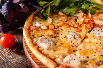 Delicious hot italian pizza sliced and served on wooden table with ingredients, close up view.