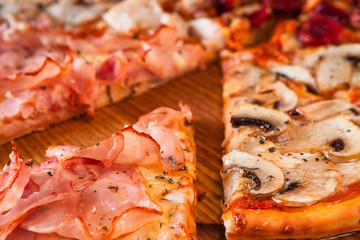 Tasty fresh italian pizza with cheese, ham, mushrooms and sausage close up. Italian traditional food.
