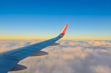 Plakat Airplane wing flying over smooth clouds and blue sky in the morning of golden time, view looking from window of aircraft