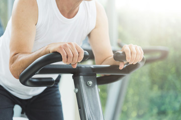 Close up senior man stretching on exercise machine before workout at the gym. copy space.