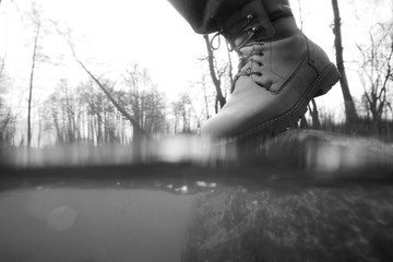 Travel concept, man fording mountain river, legs boots close-up black and white