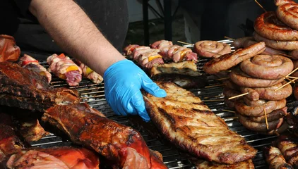 Photo sur Aluminium Cuisinier cook with blue gloves controls the cooking of grilled ribs