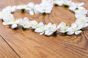Obraz na płótnie Canvas A beautiful heart of flowers. White flowers in the shape of heart on a wooden background