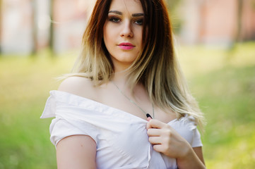 Portrait of girl with streaked hair, wear on white blouse, showing her shoulders.