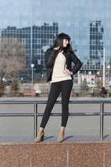 Fototapeta premium The young woman poses against the background of modern buildings.
