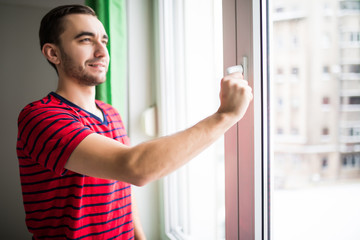 Man is opening the window at home to refresh the room in the morning