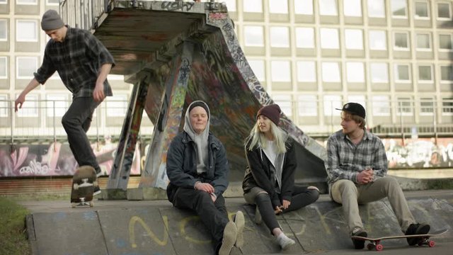 young group sitting and watching skater