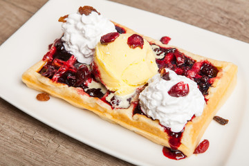 Traditional Belgian waffles with ice cream and berry fruit sauce in the plate,selective focus
