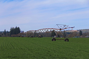 Full Three-Quarter Right Side of Frame Viewpoint, Overhead Commercial Agricultural Irrigation System on Green Farm Field, Blue Sky with Wisp of White Clouds, Daytime - Oregon, USA (HDR Image)