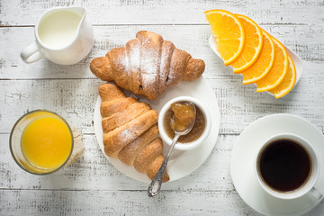 Croissant jam coffee orange jice at white wooden table. 