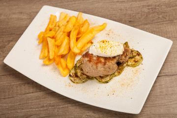 Roasted pork knuckle served in a plate with French fries and sour cream