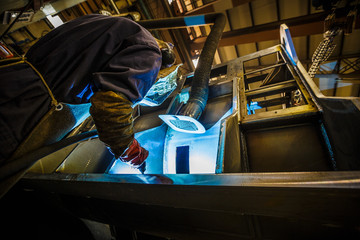 Welder at work in industrial surrondings.