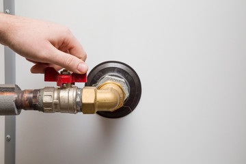 Man's hand working at water heater boiler. Plumbing.