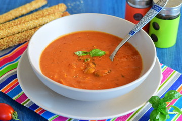 Tomato soup with mussels in a blue bowl on a blue background with bread sticks. Healthy eating concept