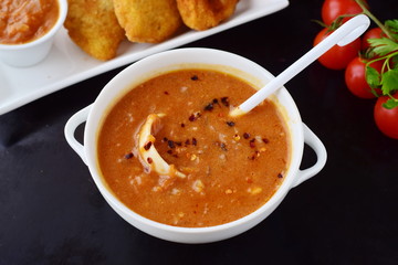 Tomato gravy for meatballs, pasta in a white bowl with potato patties on a black abstract background. Healthy food concept