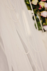 beads from pearls on a wedding ceremonial arch with a white background