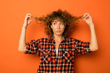 young natural curly woman standing over an orange background - obrazy, fototapety, plakaty