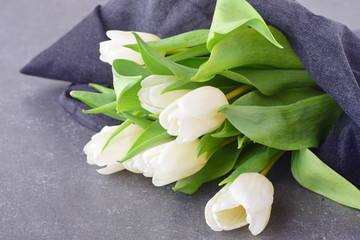 Bouquet of multicolored tulips on a grey cloth. Spring flowers. Romance.